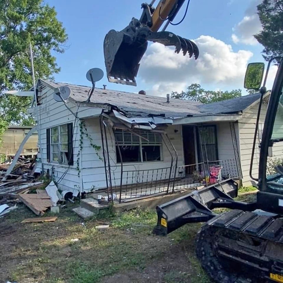 Excavator with grapple tearing down a structure during demolition in Colorado