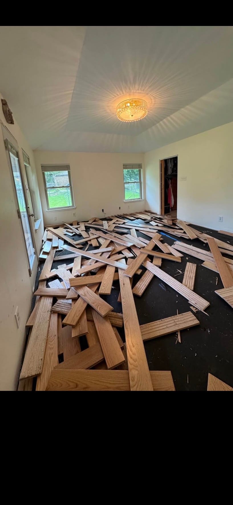Hardwood plank flooring torn up during flooring demolition, stacked for haul-away