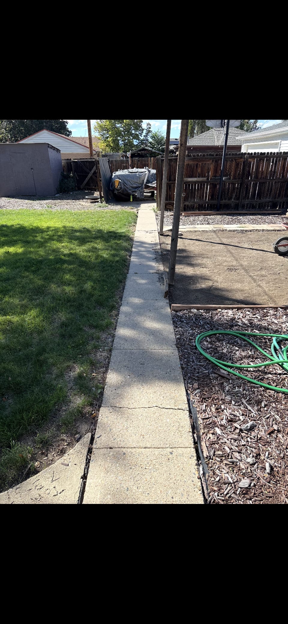 Backyard storage shed, wood privacy fence and concrete walkway before outdoor structure demolition in Colorado
